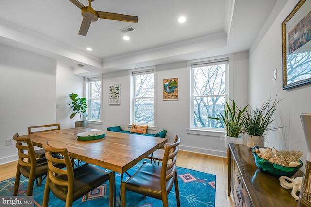 dining space featuring visible vents, light wood-style floors, and a tray ceiling