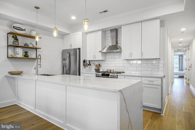 kitchen featuring visible vents, stainless steel refrigerator with ice dispenser, a sink, wall chimney range hood, and range