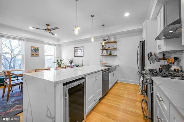 kitchen with beverage cooler, light wood-type flooring, appliances with stainless steel finishes, a peninsula, and wall chimney exhaust hood