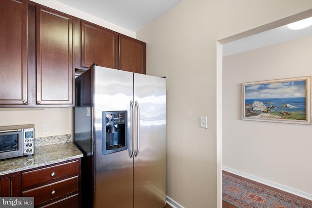 kitchen featuring light stone counters and stainless steel fridge with ice dispenser