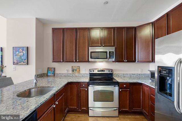 kitchen featuring light hardwood / wood-style floors, stainless steel appliances, light stone countertops, and sink