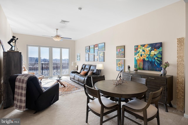 carpeted dining space with a water view and ceiling fan