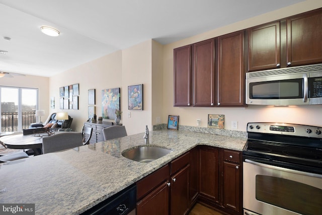 kitchen featuring sink, kitchen peninsula, ceiling fan, stainless steel appliances, and light stone countertops