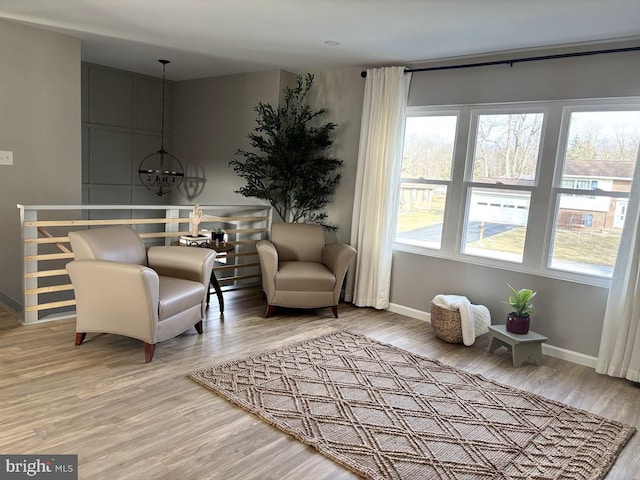 sitting room featuring wood-type flooring, a wealth of natural light, and a notable chandelier