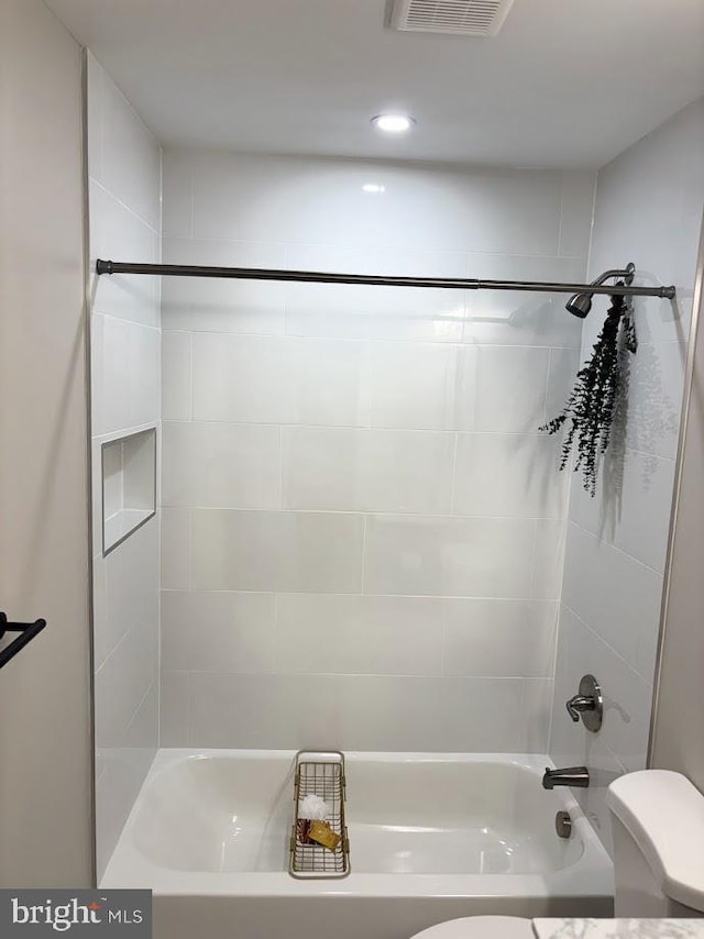 bathroom with toilet and tiled shower / bath