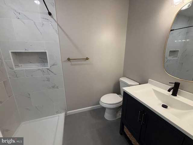 bathroom with vanity, toilet, and tiled shower