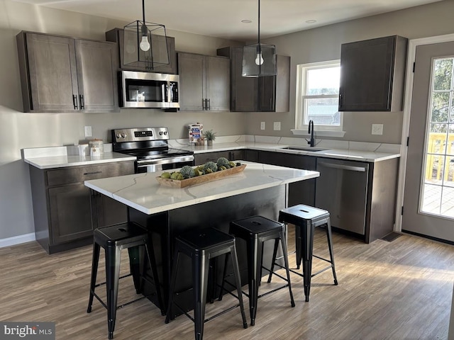 kitchen featuring sink, decorative light fixtures, a kitchen island, and appliances with stainless steel finishes