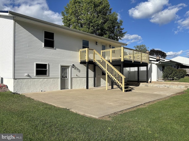 back of property with a wooden deck, a lawn, and a patio