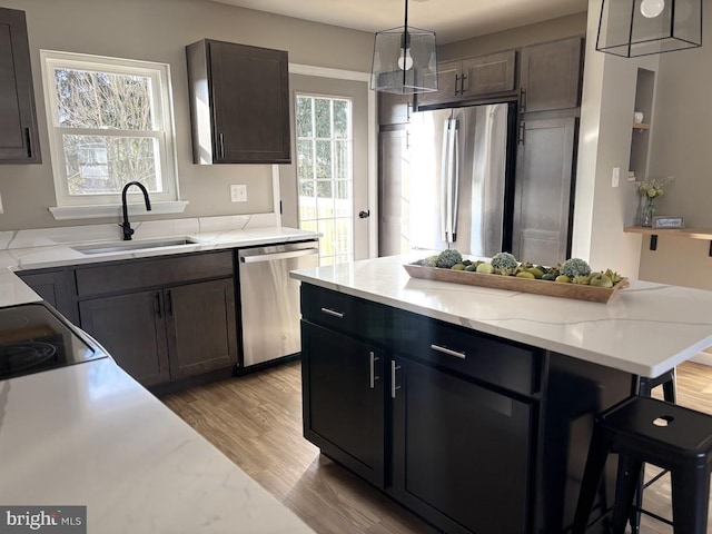 kitchen featuring pendant lighting, sink, appliances with stainless steel finishes, dark brown cabinets, and a kitchen island