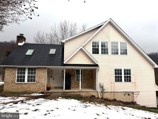 traditional-style home featuring a porch, brick siding, and a chimney