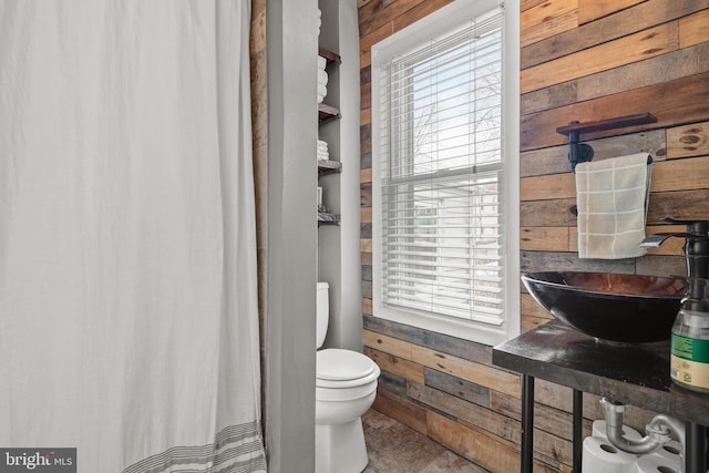 bathroom with sink, wooden walls, and toilet