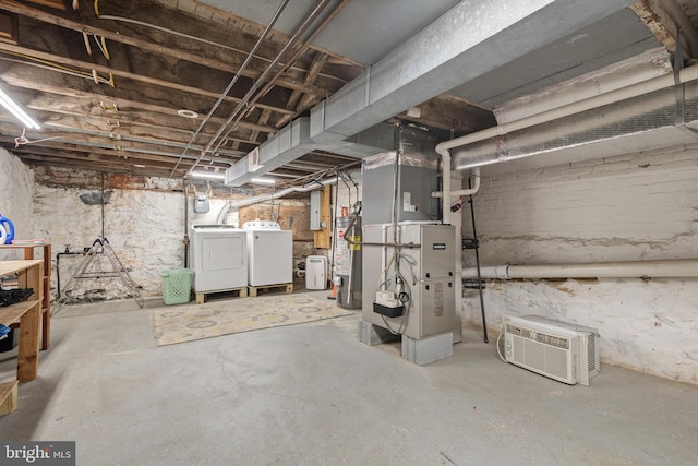 basement with washing machine and clothes dryer, heating unit, and gas water heater