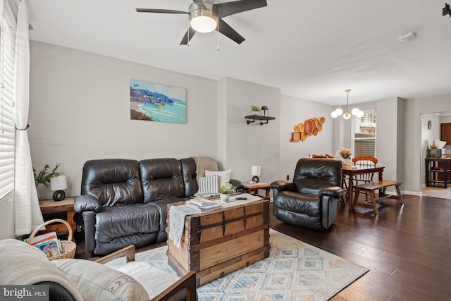 living room featuring ceiling fan with notable chandelier and dark hardwood / wood-style flooring