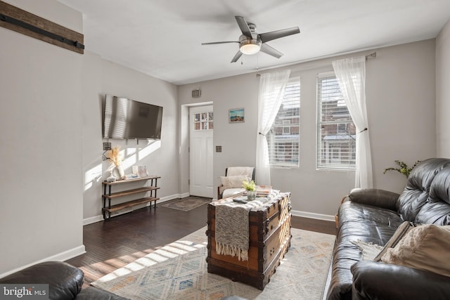 living room with a barn door, dark hardwood / wood-style floors, and ceiling fan