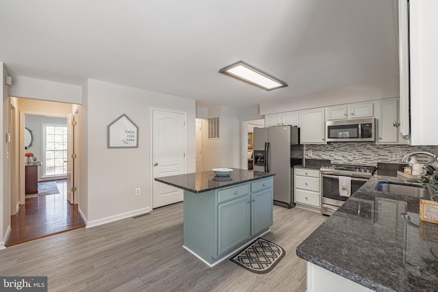 kitchen with a kitchen island, white cabinetry, sink, dark stone countertops, and stainless steel appliances