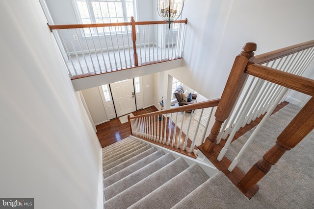 stairs featuring hardwood / wood-style flooring, a chandelier, and a high ceiling