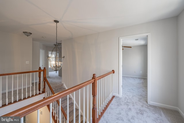 hallway featuring light carpet and an inviting chandelier