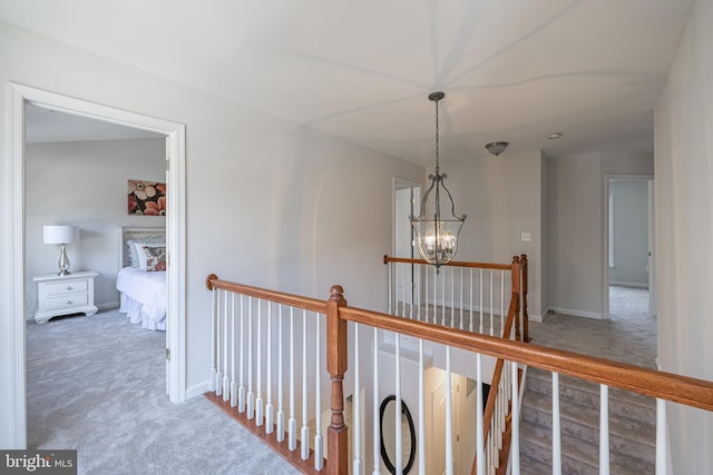 hallway with carpet floors and a notable chandelier