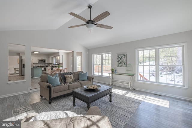 living room with ceiling fan, vaulted ceiling, and light hardwood / wood-style flooring