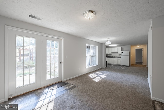 unfurnished living room featuring dark colored carpet and a textured ceiling