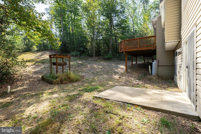 view of yard featuring a wooden deck and a patio