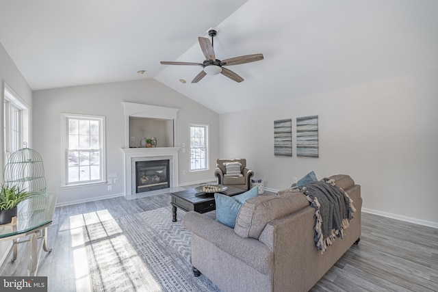 living room with hardwood / wood-style flooring, ceiling fan, lofted ceiling, and a high end fireplace