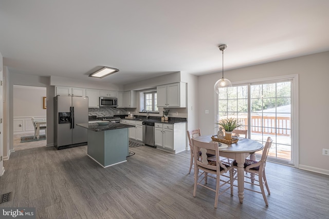 kitchen with sink, decorative light fixtures, a center island, dark hardwood / wood-style floors, and stainless steel appliances