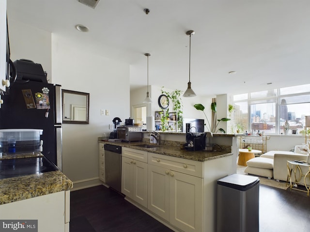 kitchen with appliances with stainless steel finishes, dark hardwood / wood-style floors, pendant lighting, sink, and dark stone countertops