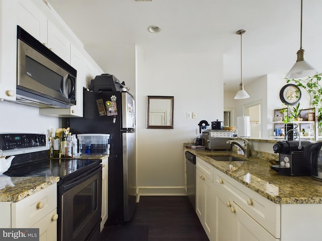 kitchen with stainless steel appliances, white cabinetry, hanging light fixtures, and dark stone countertops