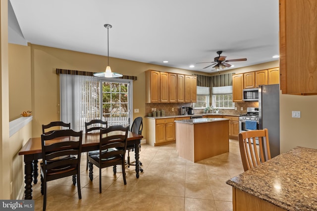 kitchen with hanging light fixtures, backsplash, stainless steel appliances, a center island, and light stone countertops