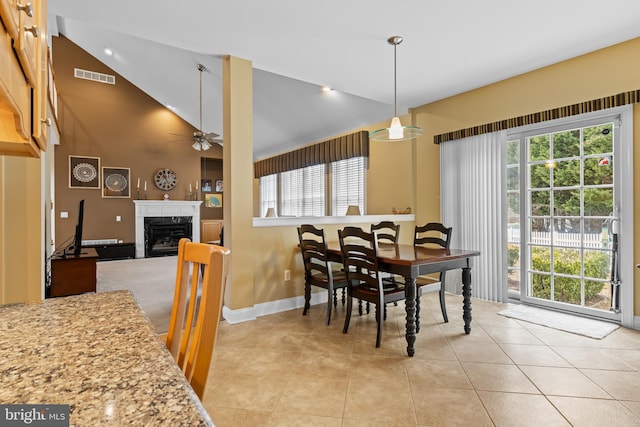 tiled dining area featuring high vaulted ceiling, a premium fireplace, and ceiling fan