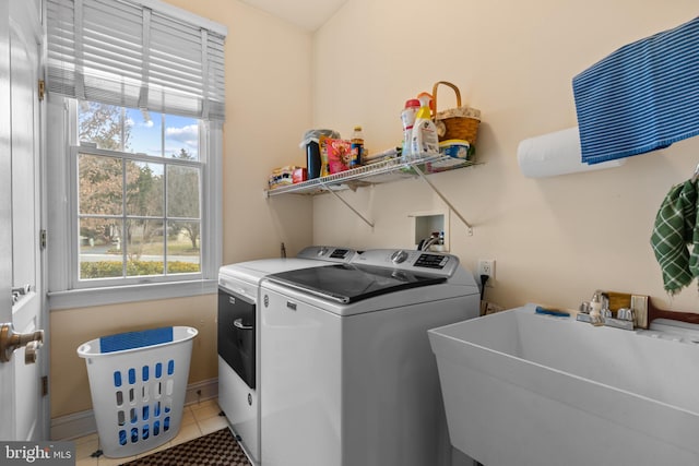 laundry room featuring washing machine and clothes dryer, a healthy amount of sunlight, sink, and light tile patterned floors