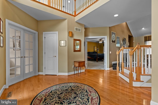 foyer featuring hardwood / wood-style flooring, high vaulted ceiling, french doors, and ceiling fan