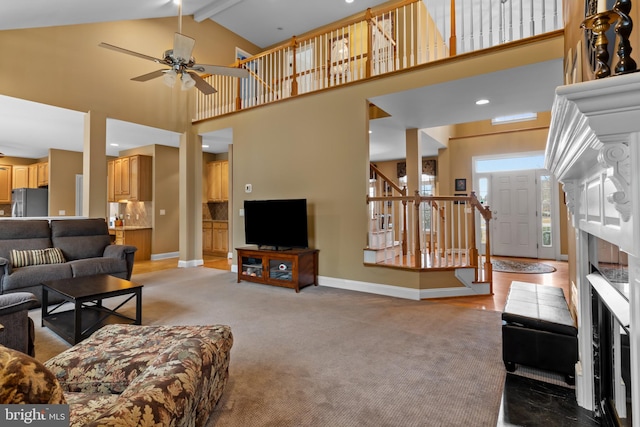 carpeted living room with ceiling fan, high vaulted ceiling, and beamed ceiling