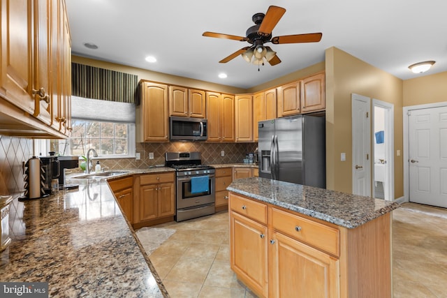 kitchen with sink, stone counters, stainless steel appliances, a center island, and decorative backsplash