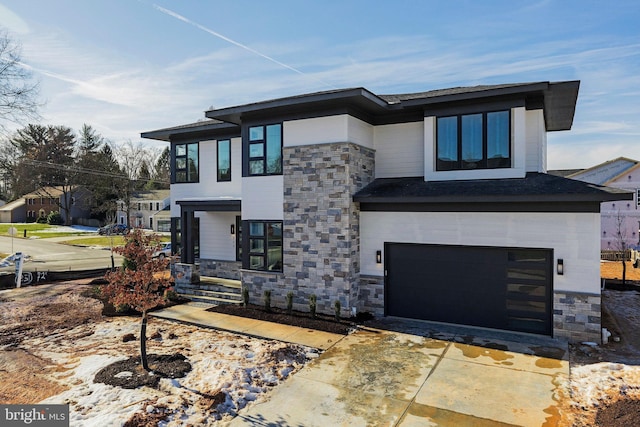 modern home featuring stone siding, an attached garage, and driveway