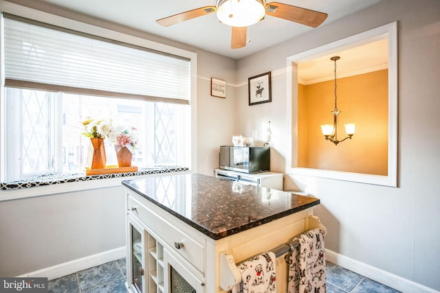 kitchen with dark stone counters, decorative light fixtures, ceiling fan with notable chandelier, and white cabinets