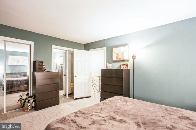 bedroom featuring light colored carpet and multiple closets