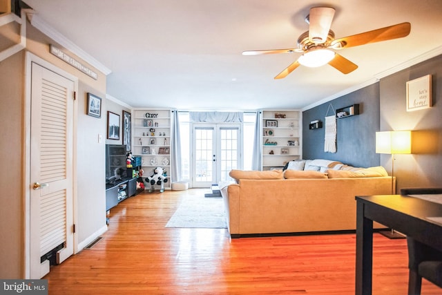 living room with hardwood / wood-style flooring, built in features, ornamental molding, and french doors