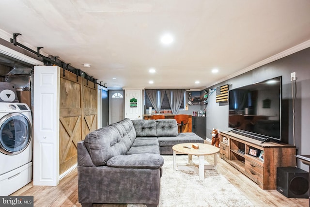 living room with washer / dryer, ornamental molding, a barn door, and light wood-type flooring