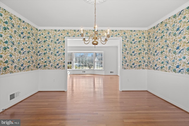 unfurnished dining area with hardwood / wood-style floors, a notable chandelier, and ornamental molding