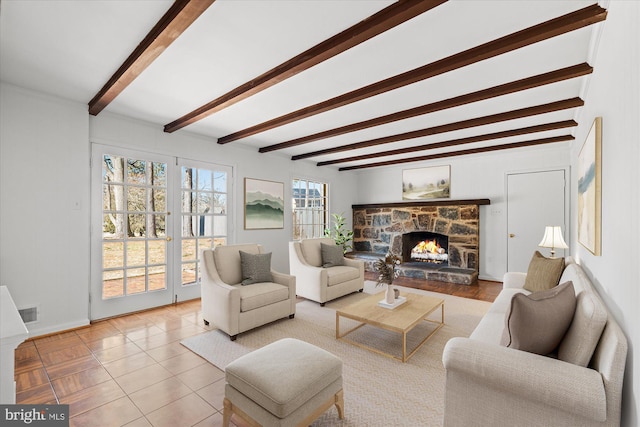 living room featuring light tile patterned floors, french doors, a stone fireplace, and beam ceiling