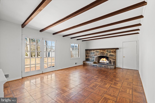 unfurnished living room with parquet flooring, beam ceiling, and a fireplace