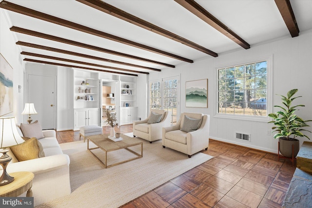 living room featuring parquet floors, a healthy amount of sunlight, built in features, and beam ceiling