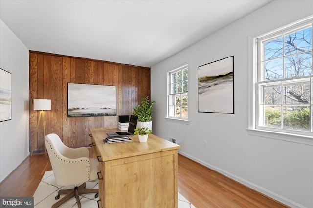 office featuring plenty of natural light, light hardwood / wood-style floors, and wood walls