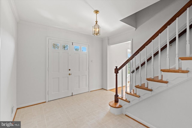 foyer entrance featuring ornamental molding and an inviting chandelier