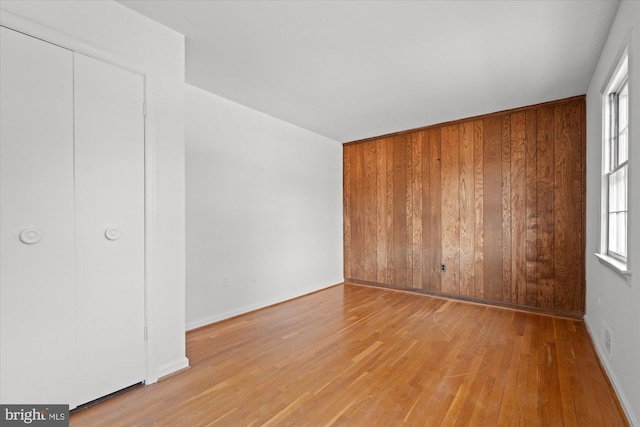 spare room with light hardwood / wood-style flooring and wooden walls