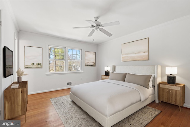 bedroom featuring ceiling fan, ornamental molding, and wood-type flooring