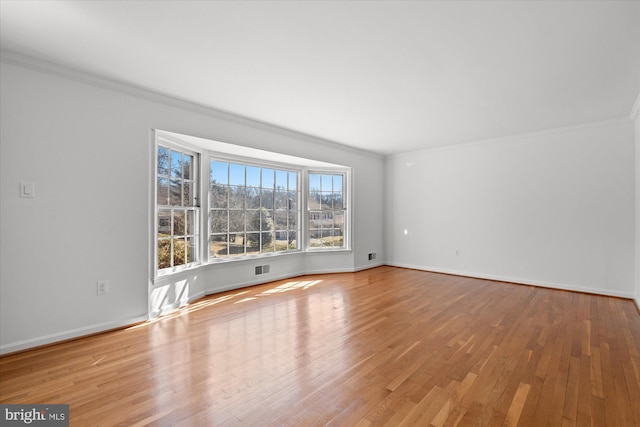 spare room featuring light hardwood / wood-style floors and crown molding