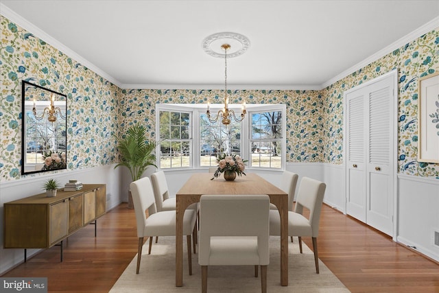 dining area featuring an inviting chandelier, wood-type flooring, and ornamental molding